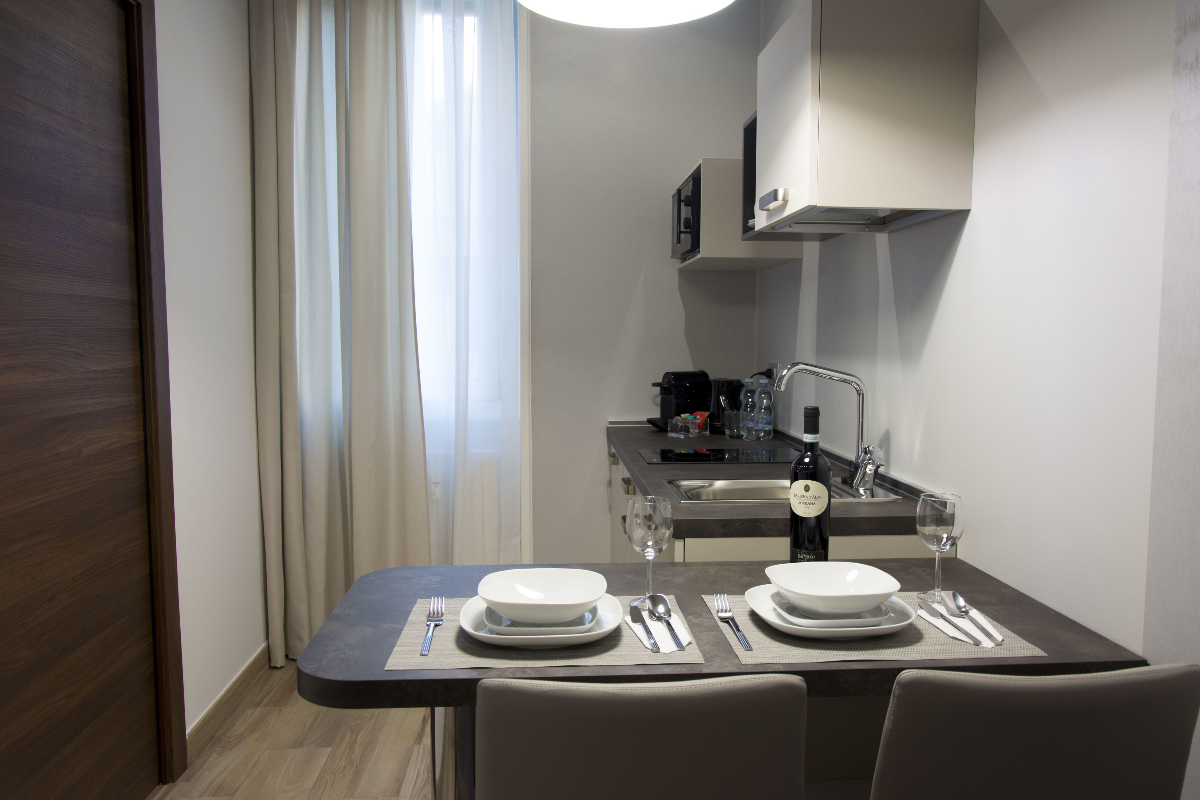 A compact kitchen with modern appliances, a dining table set for two, and a view of the adjacent living area.
