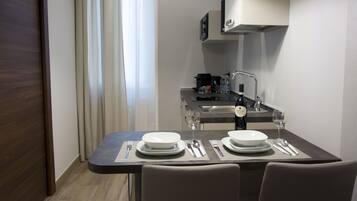 A compact kitchen with modern appliances, a dining table set for two, and a view of the adjacent living area.
