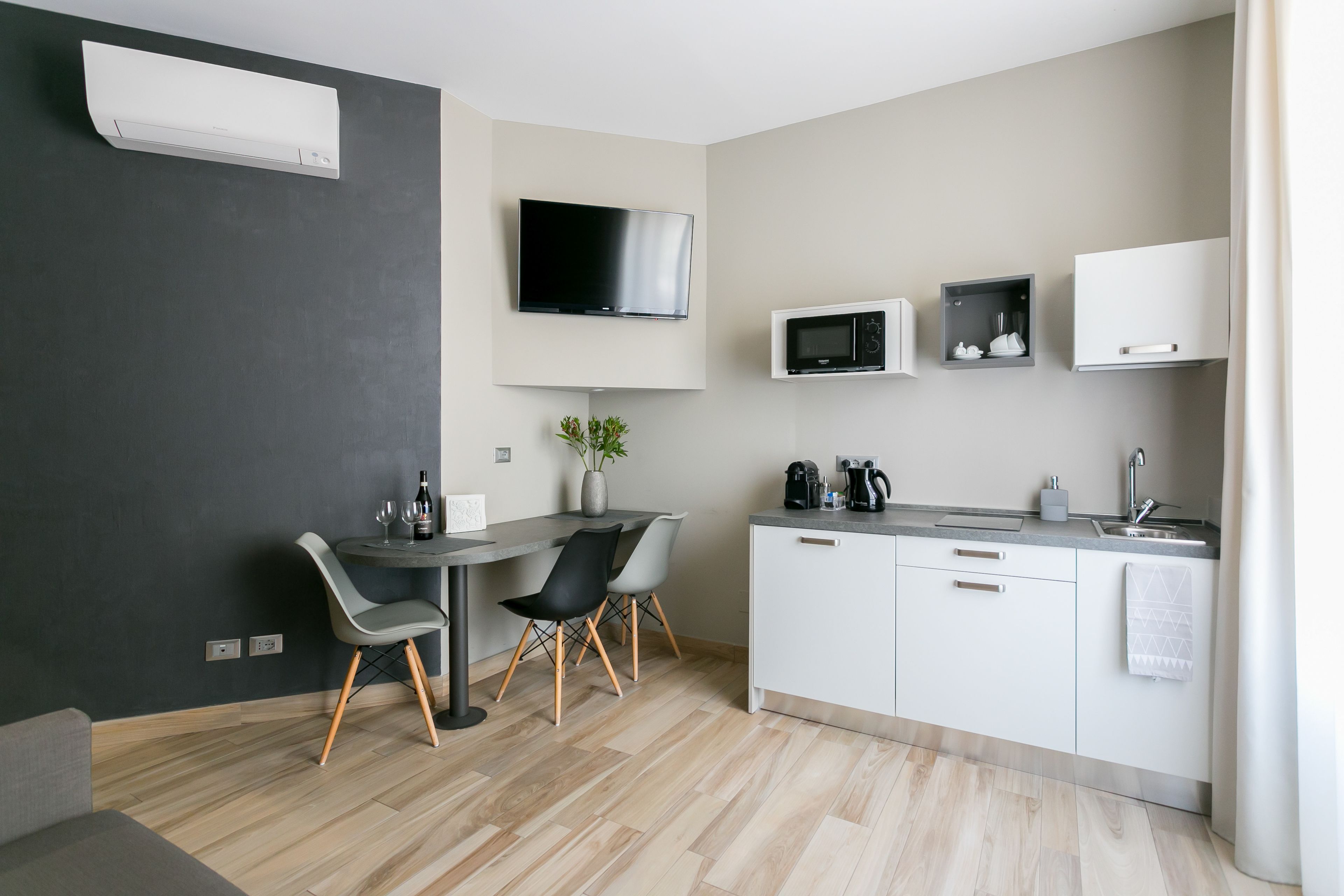 Une cuisine moderne avec un coin repas, un téléviseur à écran plat et un four à micro-ondes.