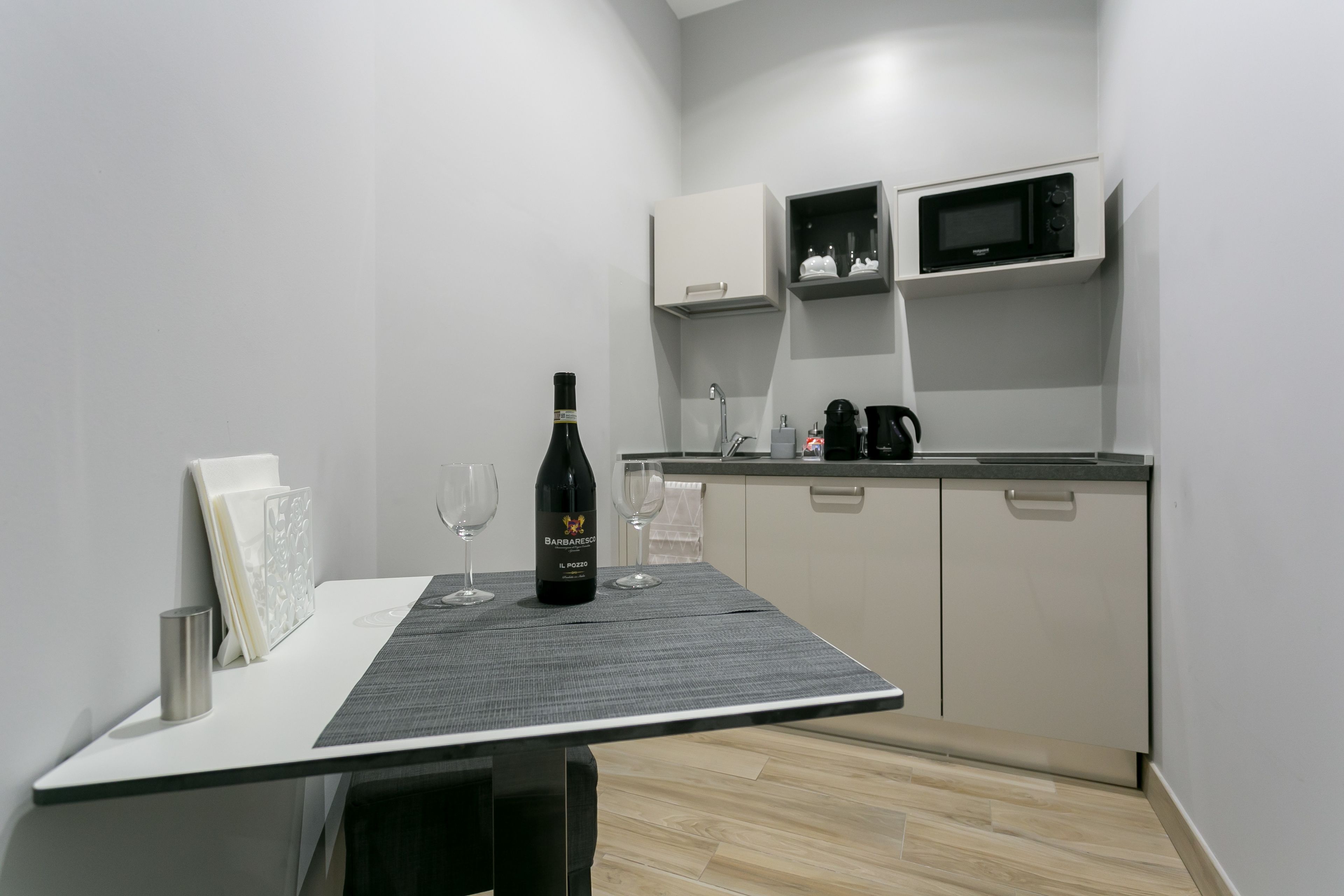 Cozinha moderna com mesa de jantar, garrafa de vinho e copos.