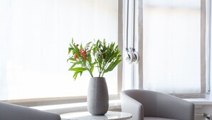 Une pièce moderne avec un canapé gris, une table ronde ornée d’un vase de fleurs et un radiateur.