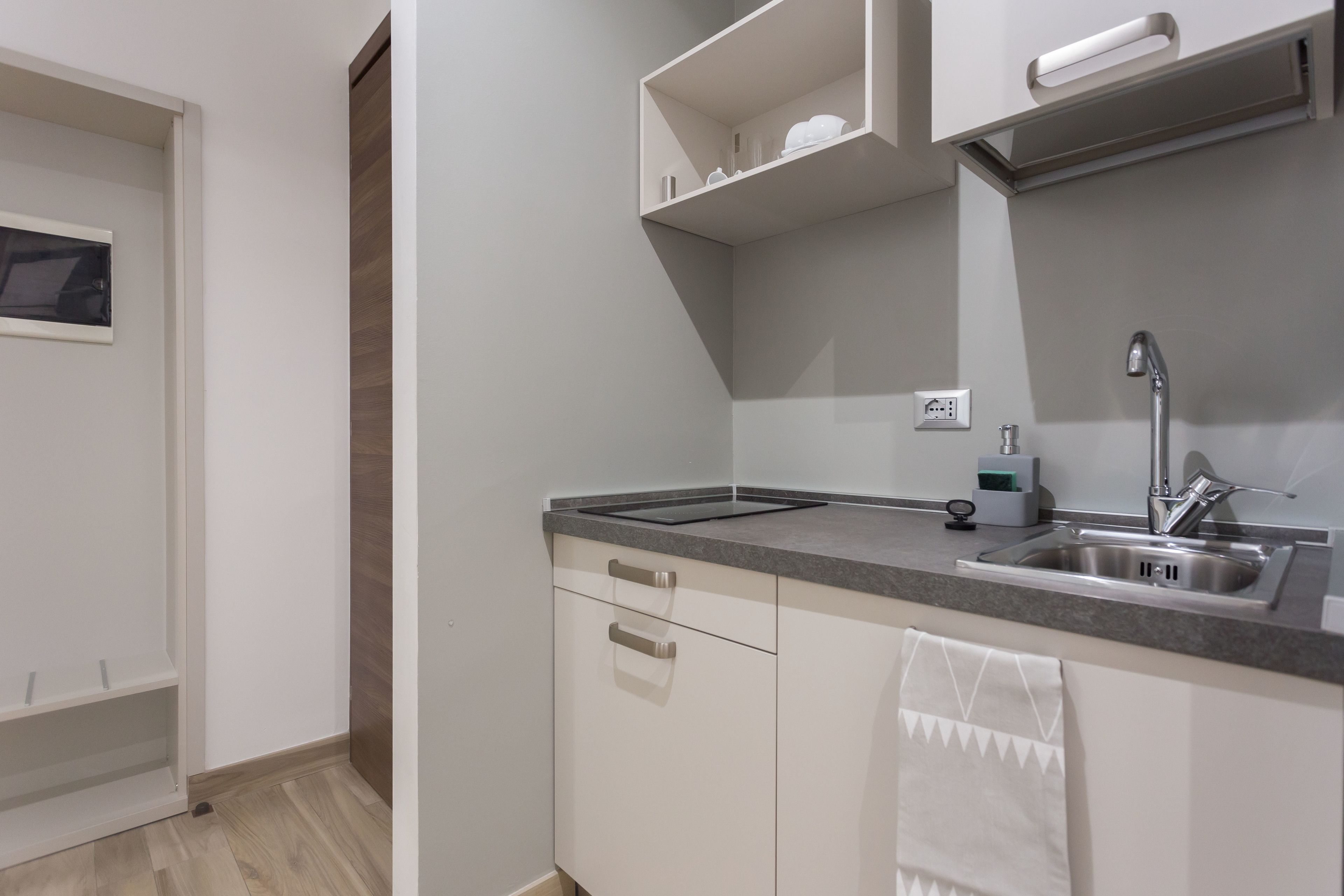 A modern kitchen with white cabinets, a stainless steel sink, and a countertop.