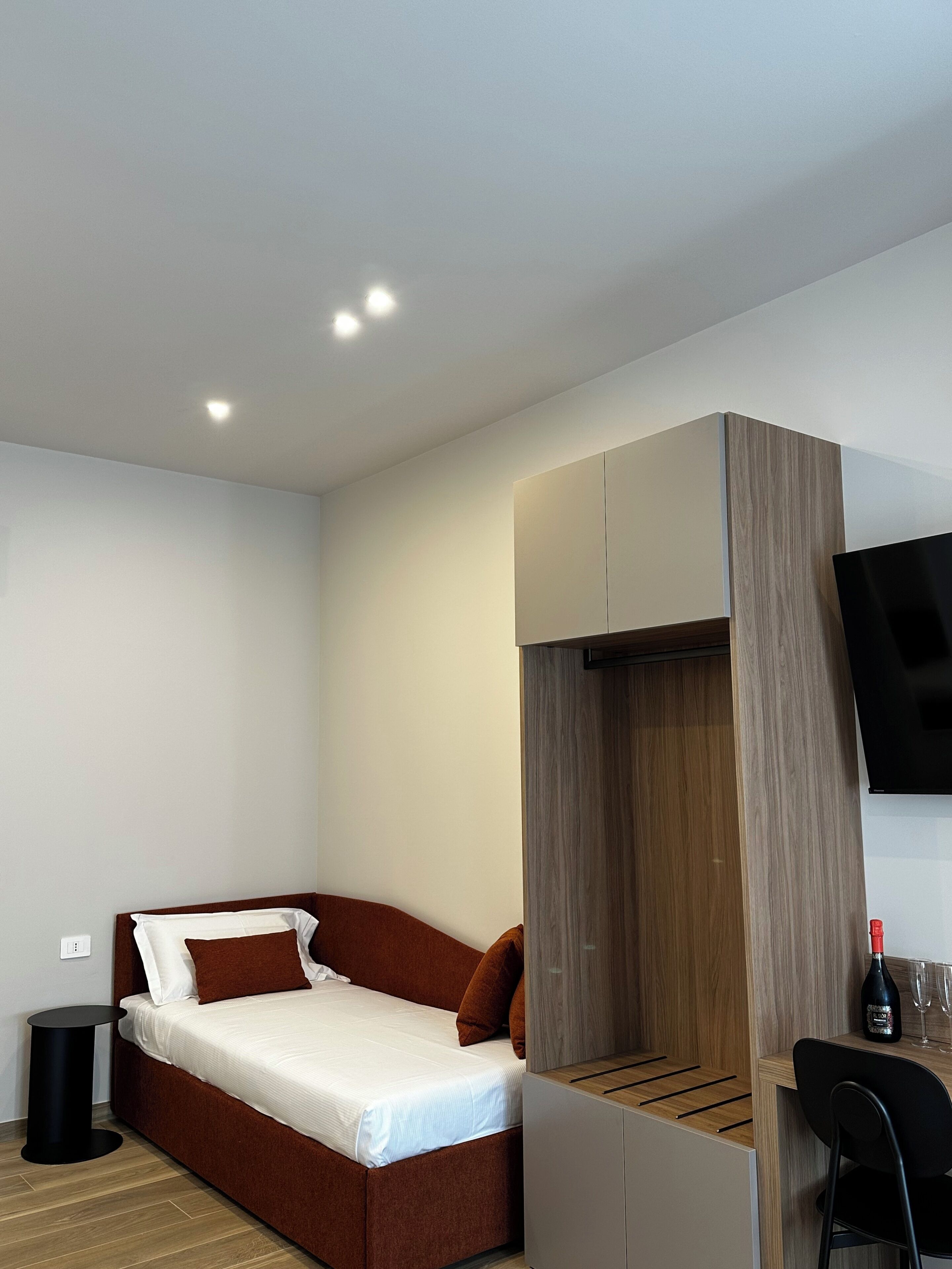 A modern bedroom with a bed, a desk, and a TV.