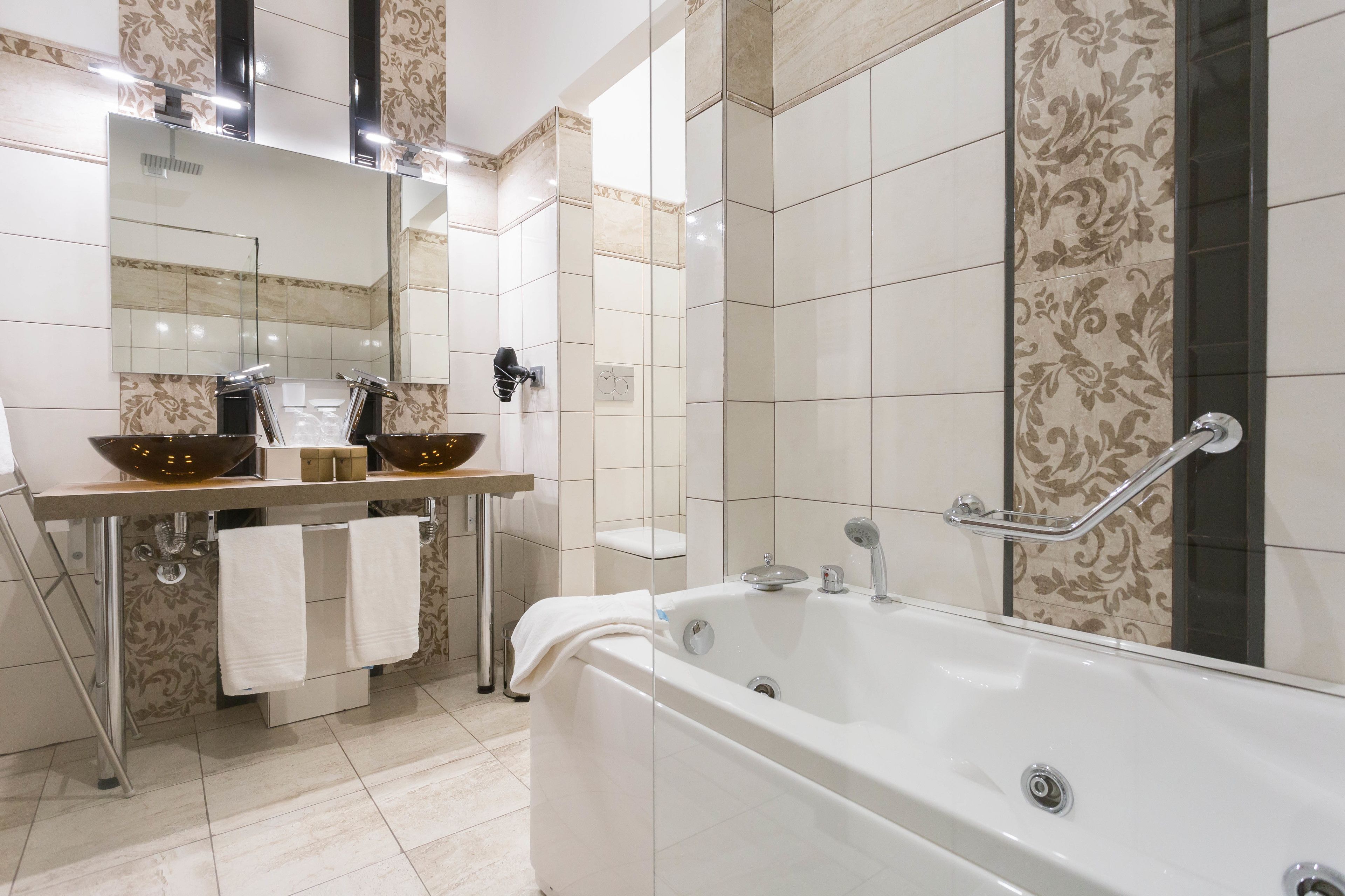 Un bany modern amb una banyera gran, un lavabo amb mirall i una zona de dutxa.