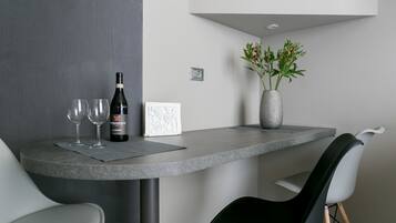 Een moderne eetruimte met een ronde tafel, twee wijnglazen, een wijnfles, een vaas met bloemen en een stoel.