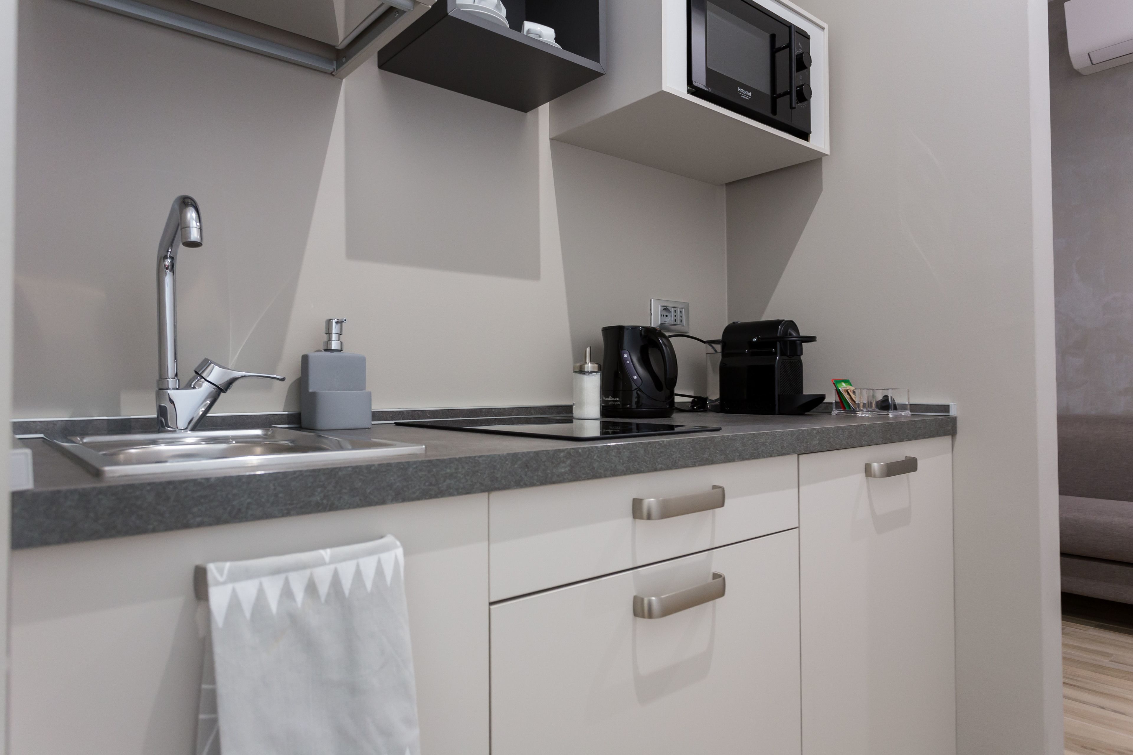 A modern kitchen with a sink, faucet, coffee maker, and microwave.