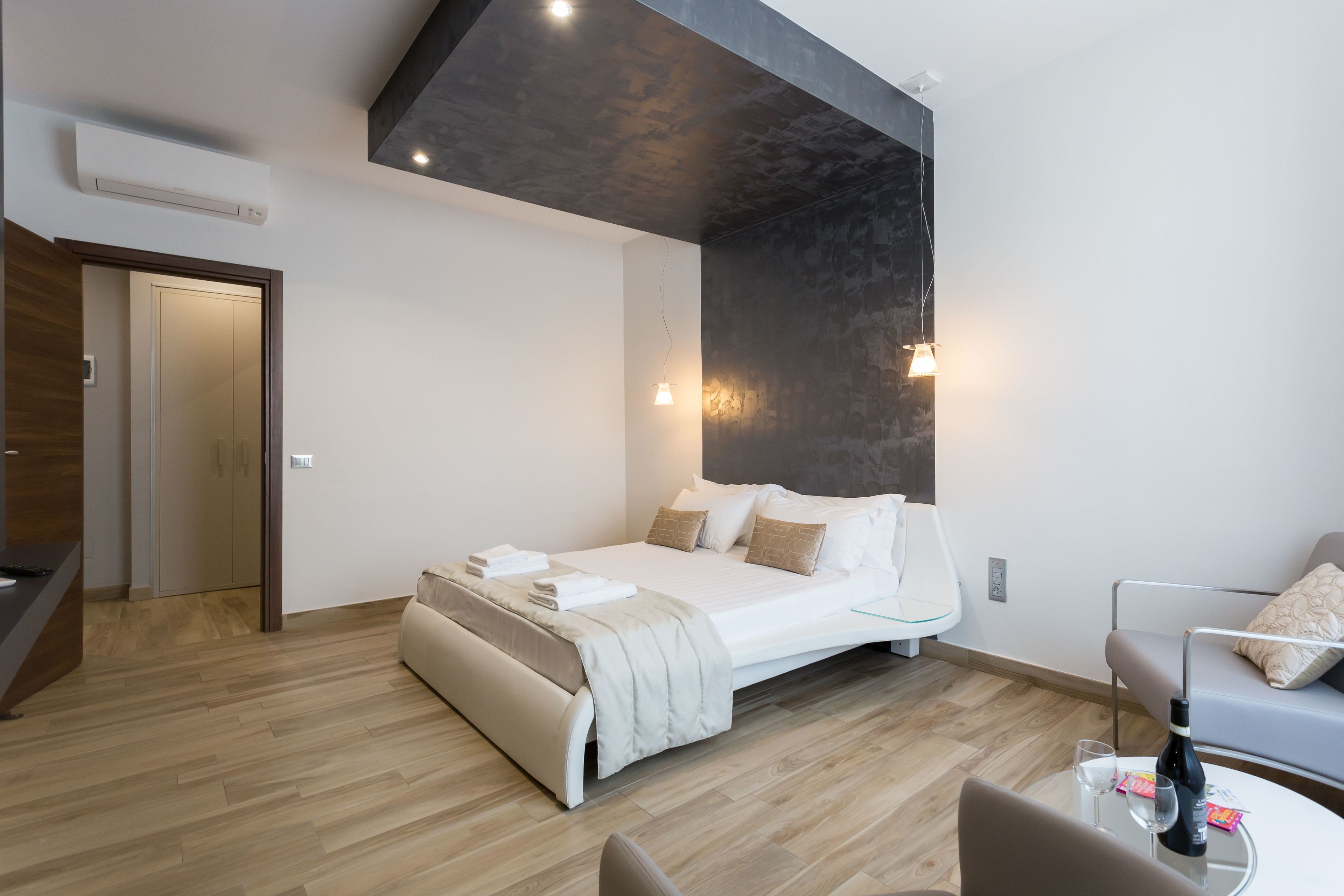 Un dormitorio moderno con cama, mesita de noche y una pequeña zona de estar con mesa y silla.