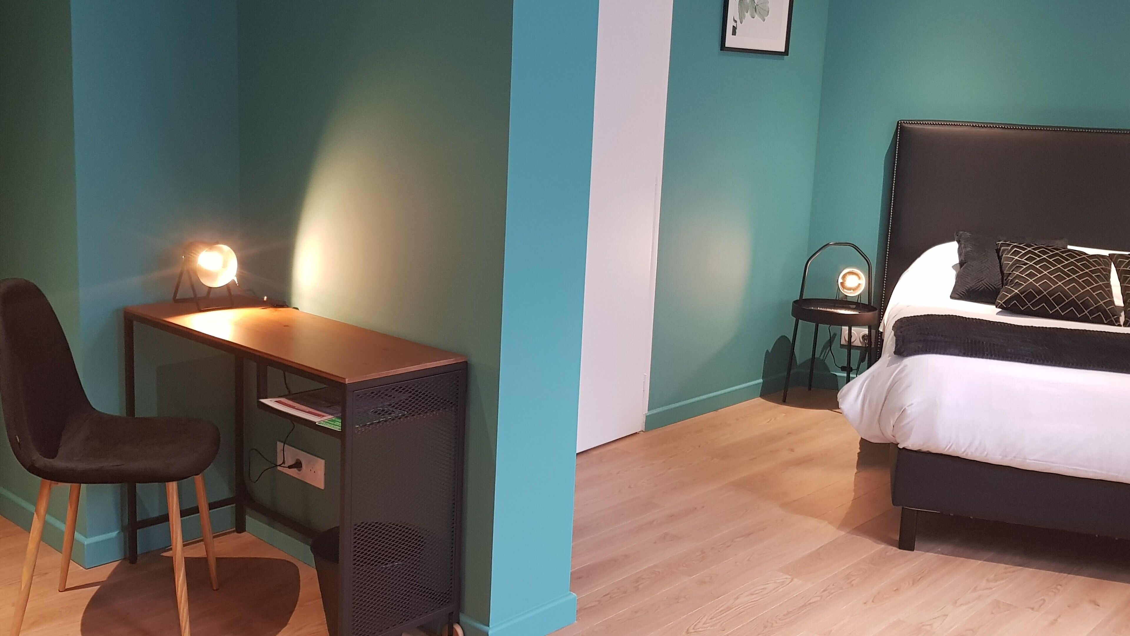 A bedroom with a bed, a desk, and a chair.