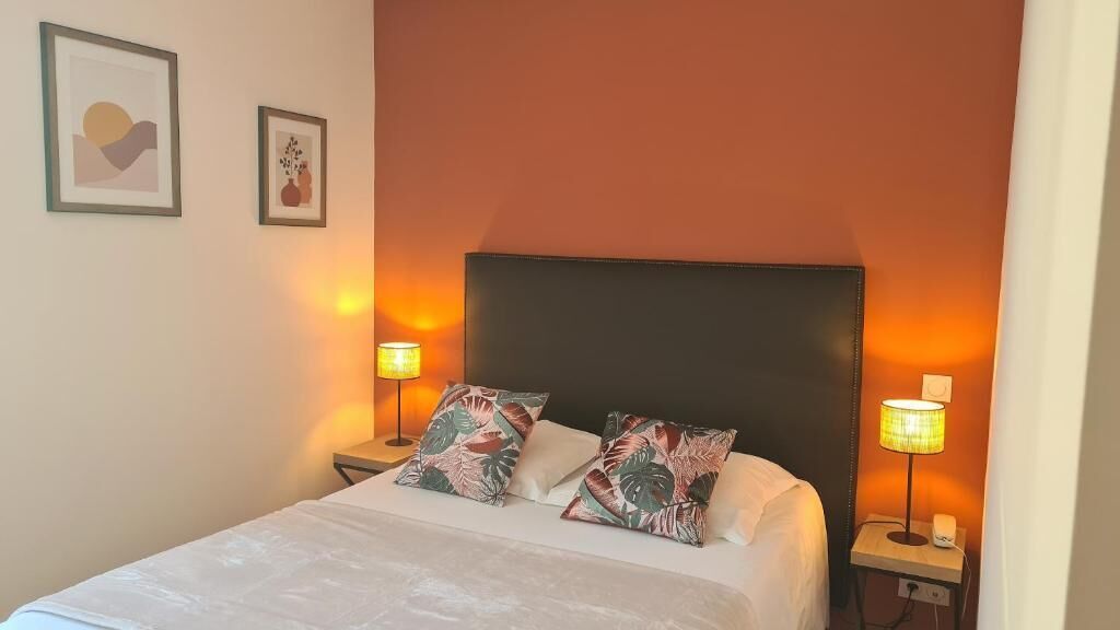 A neatly made bed with floral pillows, two bedside lamps, and framed artwork on the wall.