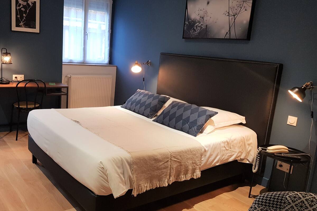 A bedroom with a bed, bedside lamps, a desk, and a chair.
