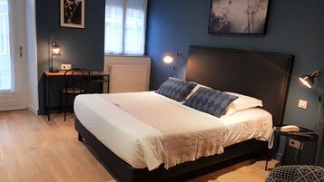 A bedroom with a bed, bedside lamps, a desk, and a chair.