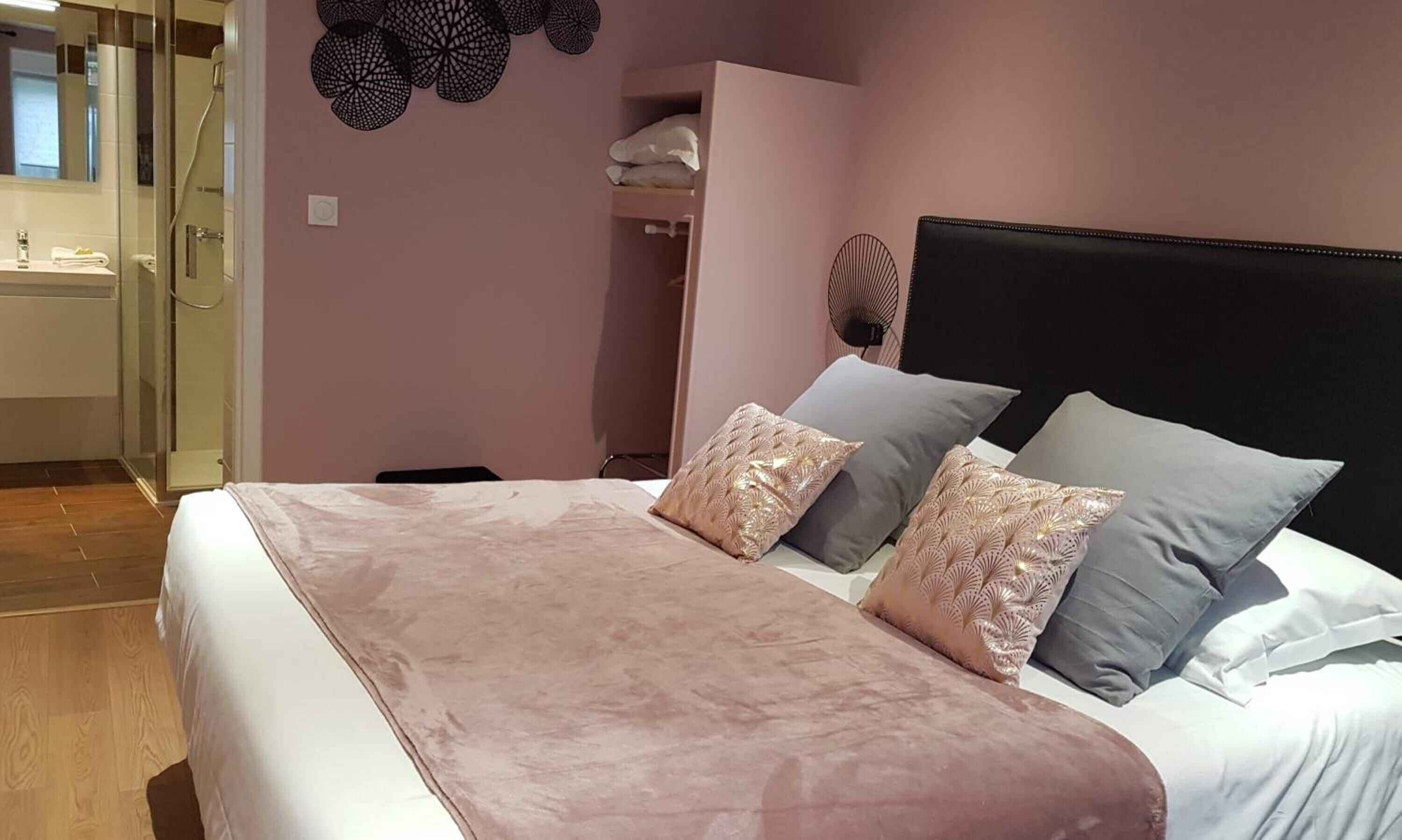 A bedroom with a bed, a bedside table, a mirror, a wardrobe, and a bathroom with a shower.