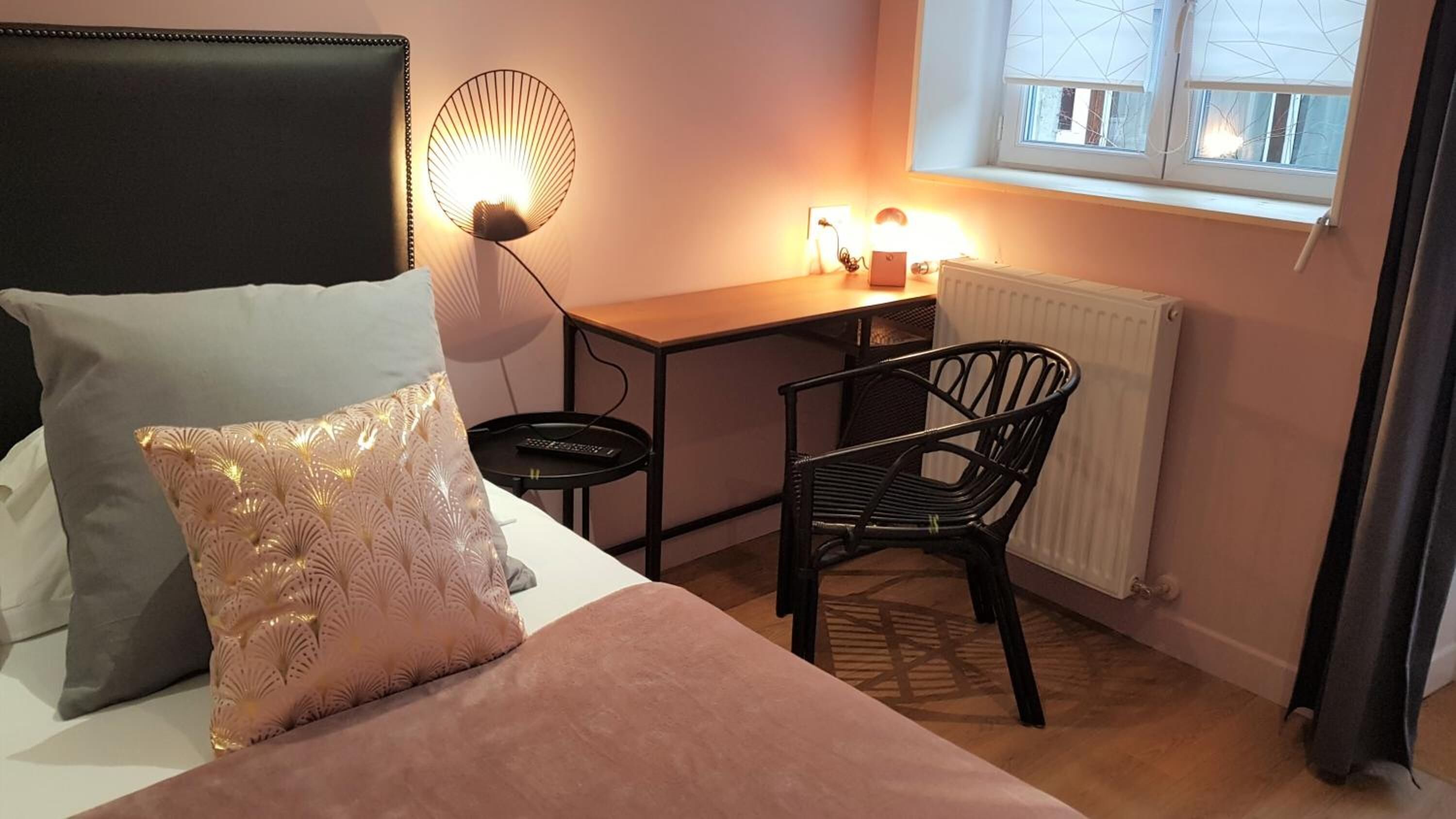 A bedroom with a bed, a desk, a chair, and a radiator.