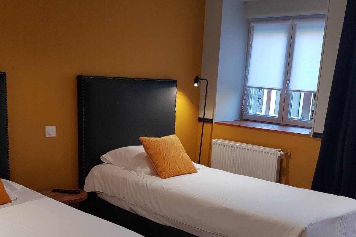 A hotel room with two single beds, a window with a view, and a radiator.