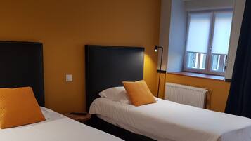 Habitación de hotel con dos camas individuales, una ventana con vistas y un radiador.
