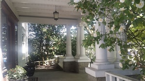 A covered porch with white columns, potted plants, and a hanging lantern. - Evermore Guesthouse (Portland)
