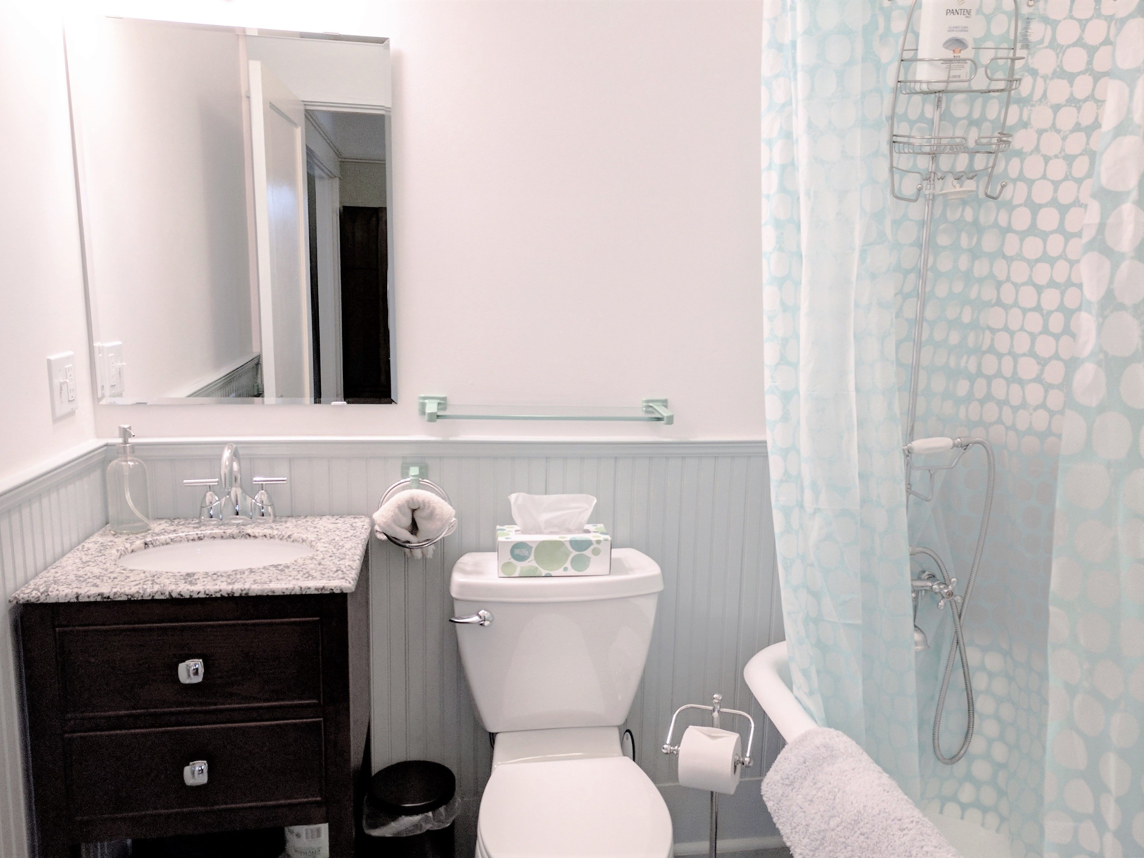 A bathroom with a white sink, dark vanity, toilet, and shower curtain.