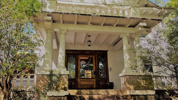 A white house with a porch supported by columns, a wooden door, and a small window. - Evermore Guesthouse (Portland)