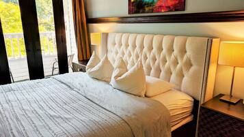 A neatly made bed with a tufted headboard, a bedside table with a lamp, and a painting on the wall.