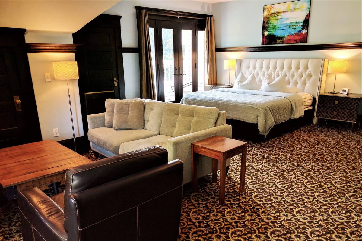 Une chambre d’hôtel avec un canapé, un lit, une table en bois et un tapis à motifs.