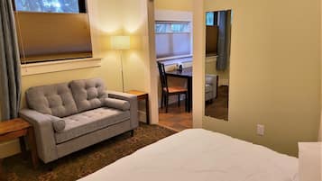 A hotel room with a bed, a sofa, a desk, and a chair.