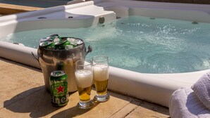 A hot tub with two glasses of beer and a can of Heineken.