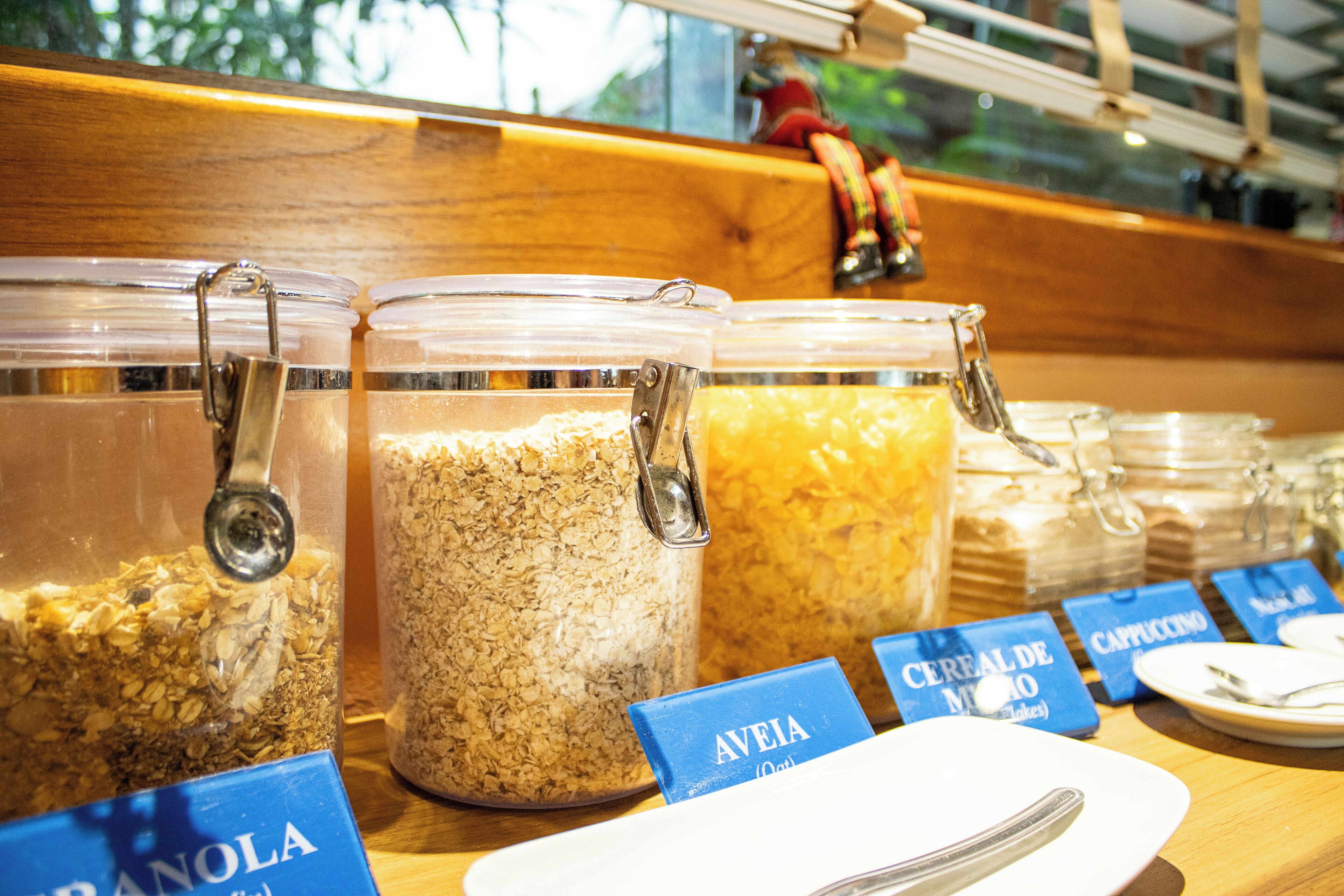 A breakfast buffet with labeled containers of granola and cereal.
