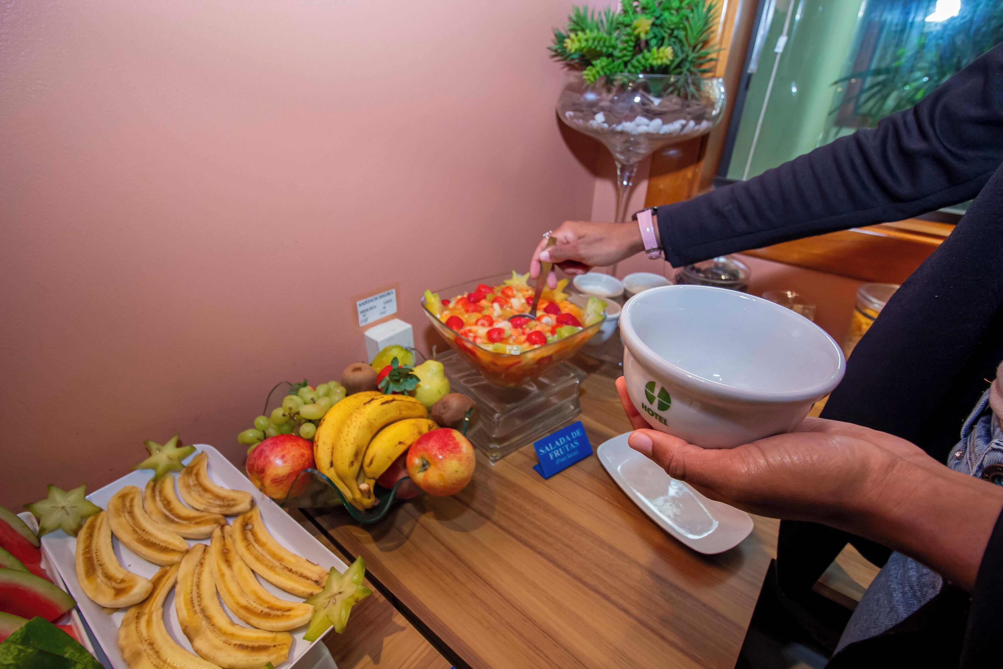 Una mesa de buffet con plátanos en rodajas, manzanas y una ensalada de frutas.