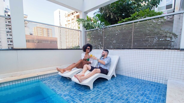 A poolside area with two lounge chairs and a tiled pool. - Hotel Dan Inn São José do Rio Preto By Nacional Inn  (São José do Rio Preto)