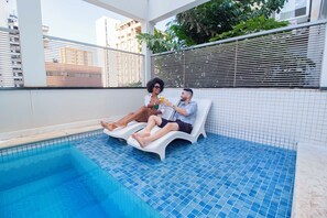 A poolside area with two lounge chairs and a tiled pool. - Hotel Dan Inn São José do Rio Preto By Nacional Inn  (São José do Rio Preto)