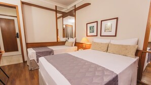 A hotel room with two beds, wooden flooring, a mirror, two framed pictures, and a bedside table with a lamp. - Hotel Dan Inn São José do Rio Preto By Nacional Inn  (São José do Rio Preto)