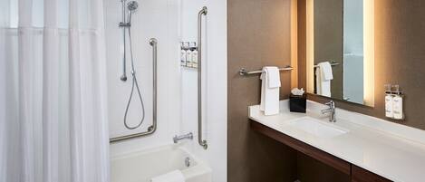 A modern bathroom with a shower, bathtub, vanity, and a large mirror.