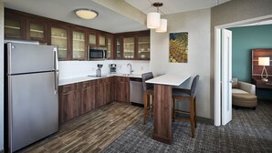 Une cuisine moderne avec des meubles en bois, des appareils électroménagers en acier inoxydable et un petit coin repas comprenant une table et des chaises.