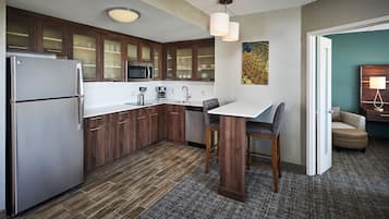 A modern kitchen with wooden cabinets, stainless steel appliances, and a small dining area with a table and chairs.