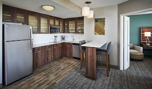 Een moderne keuken met houten kastjes, roestvrijstalen apparatuur en een kleine eethoek met een tafel en stoelen.