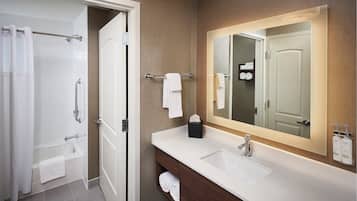 A modern bathroom with a glass shower enclosure, a white sink, and a large mirror.