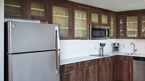 Une cuisine moderne avec des meubles en bois, des appareils électroménagers en acier inoxydable et un dosseret carrelé.