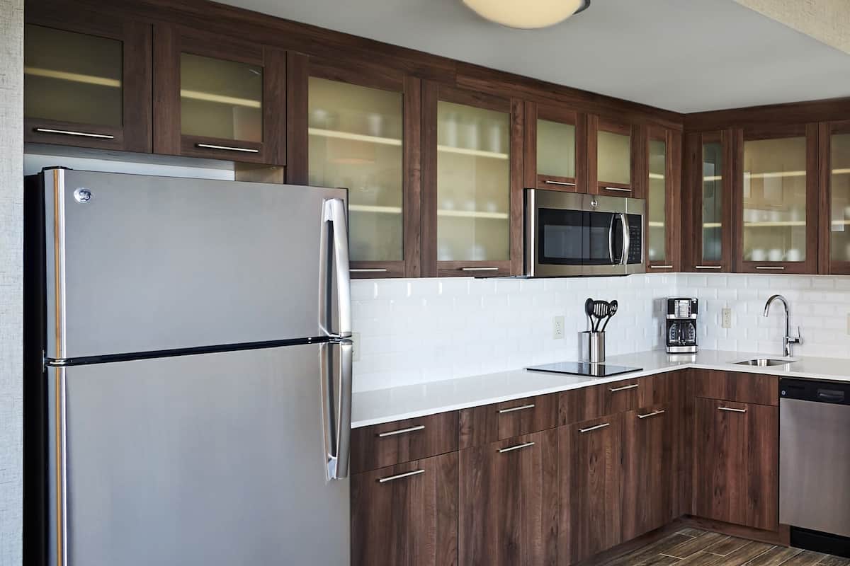Une cuisine moderne avec des meubles en bois, des appareils électroménagers en acier inoxydable et un dosseret carrelé.