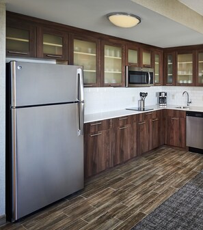 Een moderne keuken met houten kastjes, roestvrijstalen apparatuur en een betegelde achterwand.