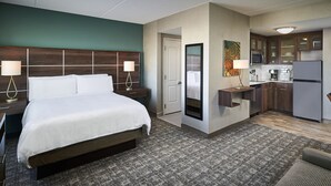 Une chambre d’hôtel comprenant un lit, des lampes de chevet, une petite kitchenette et un coin repas.