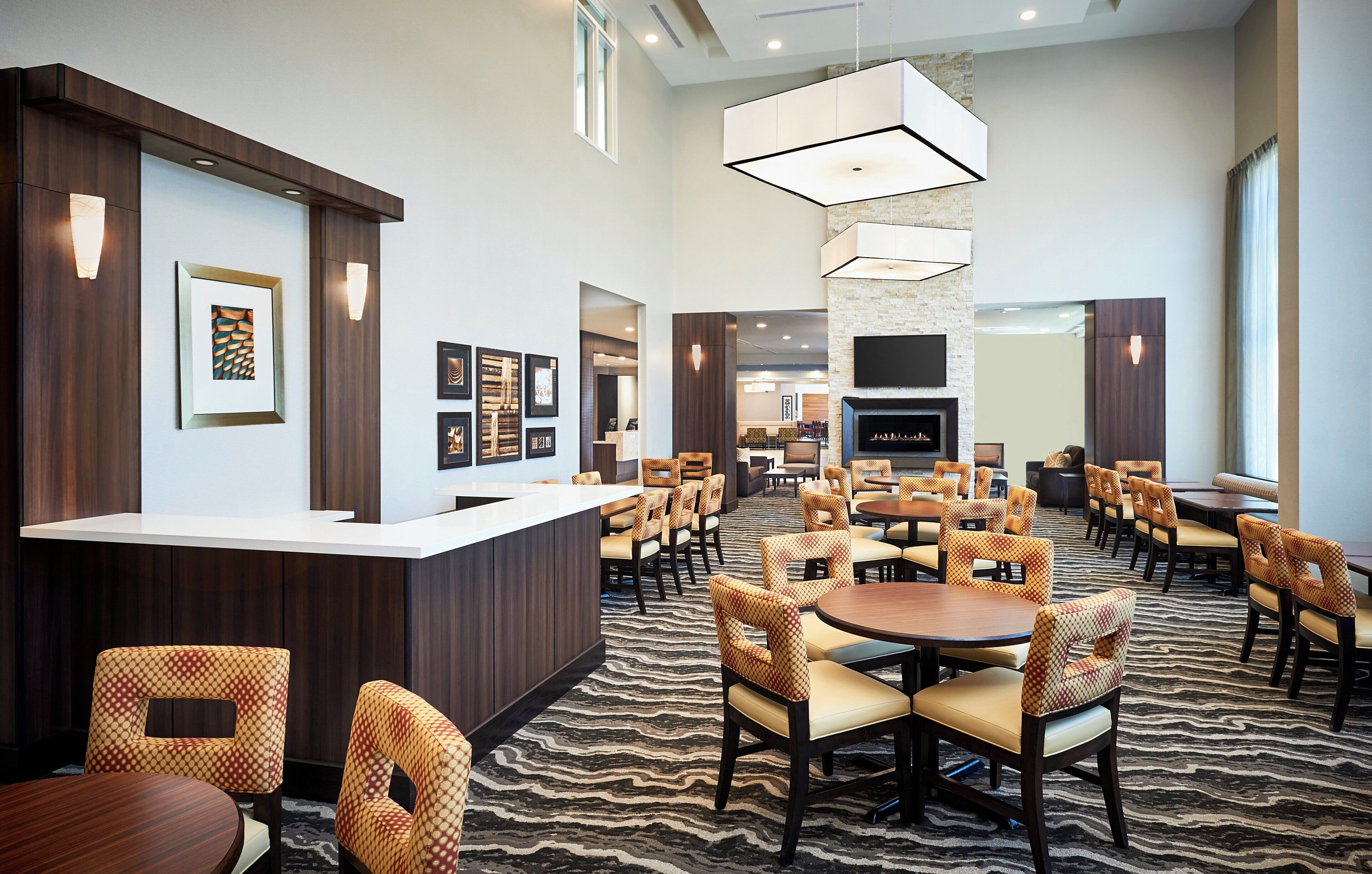 A hotel lobby with a reception desk, seating area, and a fireplace.