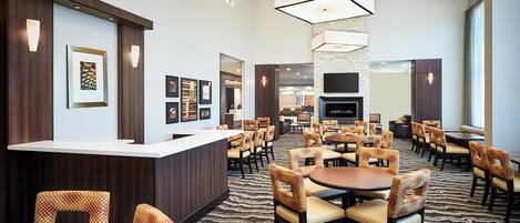 A hotel lobby with a reception desk, seating area, and a fireplace.