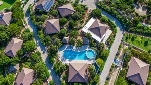 Oversigtsbillede af et boligområde med flere huse, en swimmingpool og solpaneler.