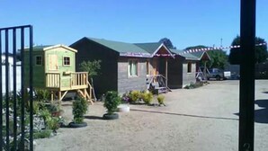 A row of cabins with a gravel driveway and a wooden deck. - Cabanas Patricia en Horcon (Puchuncavi)