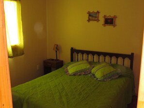 Una habitación con una cama, una mesita de noche y dos cuadros colgados en la pared.