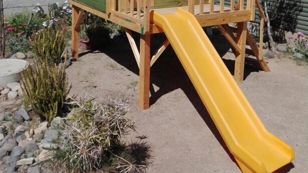 A wooden playhouse with a yellow slide, surrounded by rocks and desert plants. - Cabanas Patricia en Horcon (Puchuncavi)