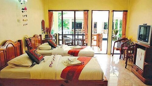 A hotel room with two beds, a TV, and a balcony with chairs. - Chaya Resort (Krabi)