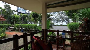 A covered outdoor seating area with a view of a road and greenery, a sign indicating a location, and a table with bottles. - Chaya Resort (Krabi)