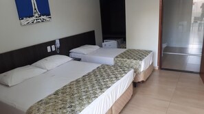 Une chambre d’hôtel avec deux lits, un téléphone, une petite table et un tableau au mur.