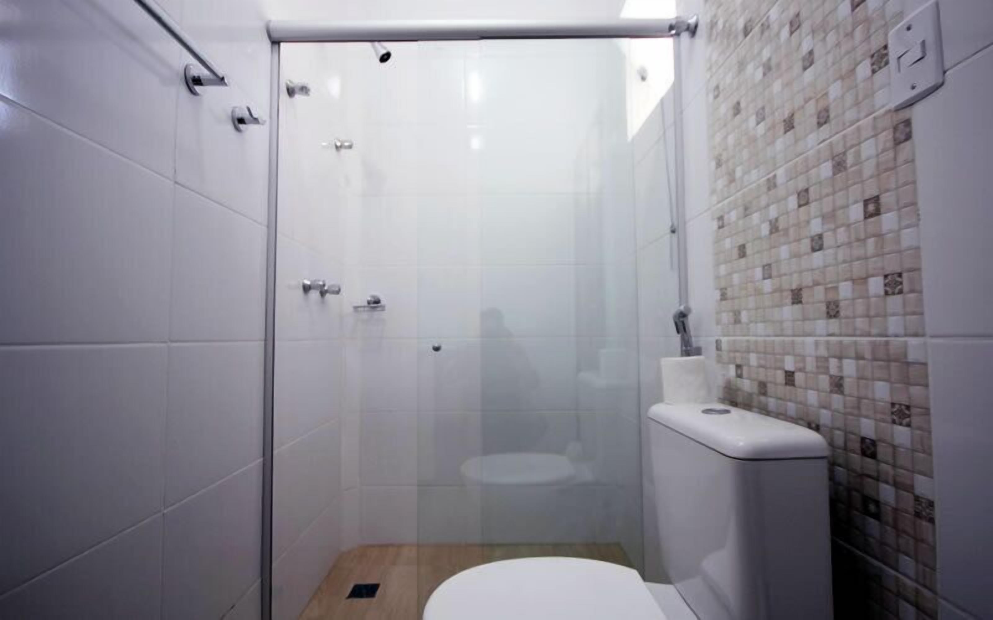 A small, modern bathroom with a glass-enclosed shower, a toilet, and a tiled wall.